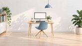Illustration av en ljus designstudio med skrivbord, blå stol, bildskärm och ritplatta.